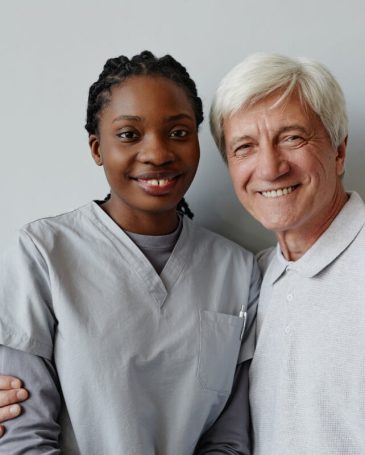 Waist up portrait of black young woman as nurse and senior man smiling at camera together